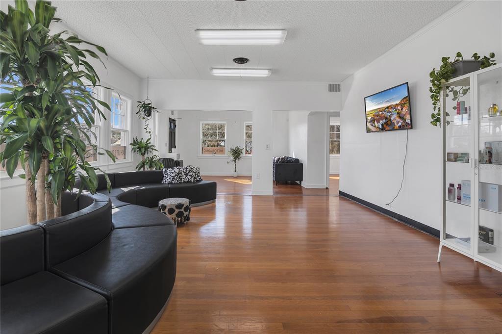 A spacious waiting room features hardwood floors, curved black leather seating, and a wall-mounted television — 120 S DILLARD STREET, WINTER GARDEN, FL