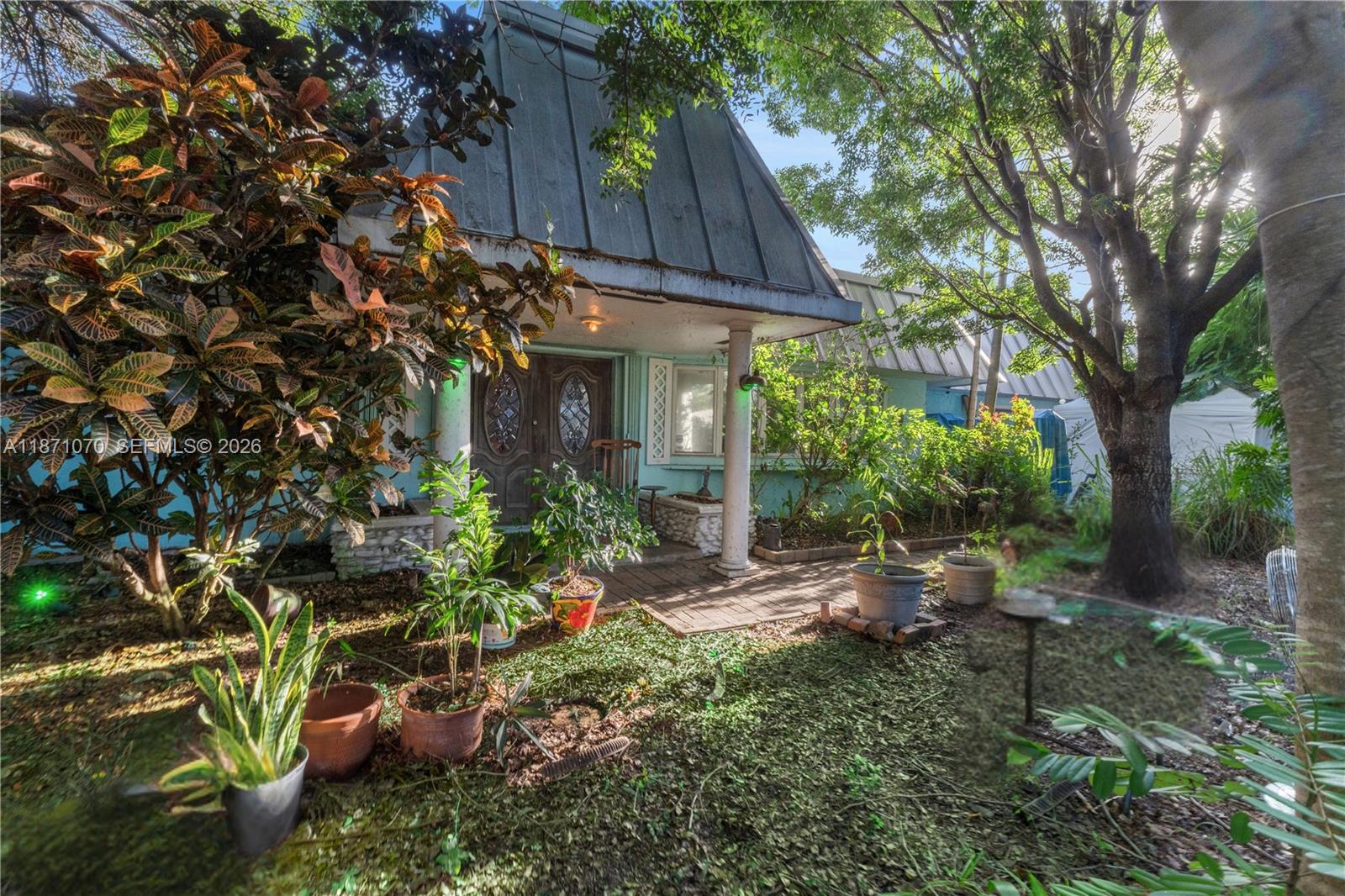 A house with a metal roof and a front porch surrounded by trees and plants — 3260 Lakeview Dr, Pompano Beach FL 33062, POMPANO BEACH, FL