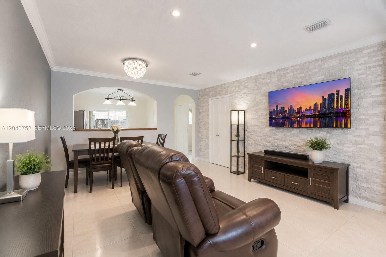 A living room features a stone accent wall, a mounted television, and a dining area — 3539 W 76th St # 6, Hialeah FL 33018, HIALEAH, FL