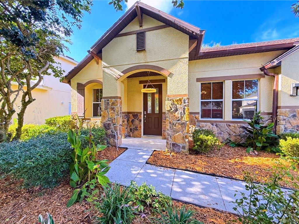 A single-story house with a stone-accented facade, a covered entryway, and a concrete walkway — 10250 MALPAS POINT, ORLANDO, FL