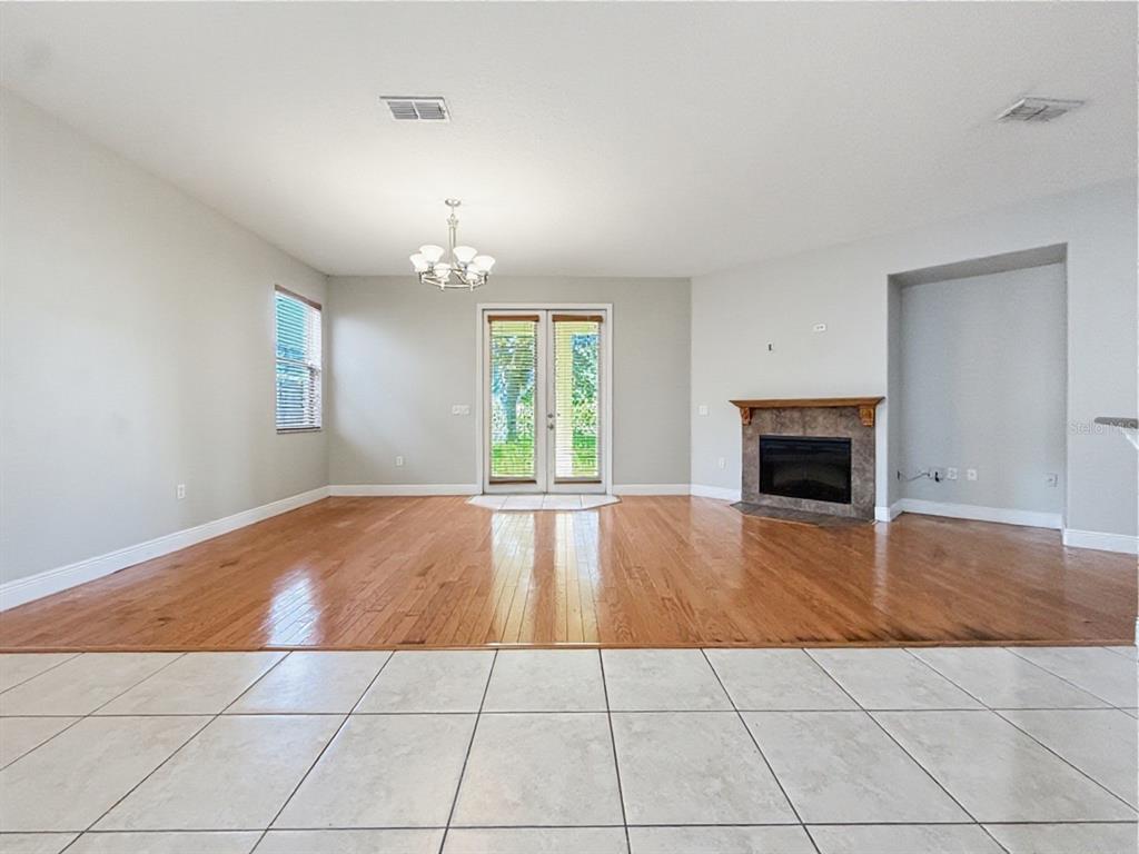 A living room with hardwood floors, a fireplace, and glass doors leading to the outdoors — 10250 MALPAS POINT, ORLANDO, FL