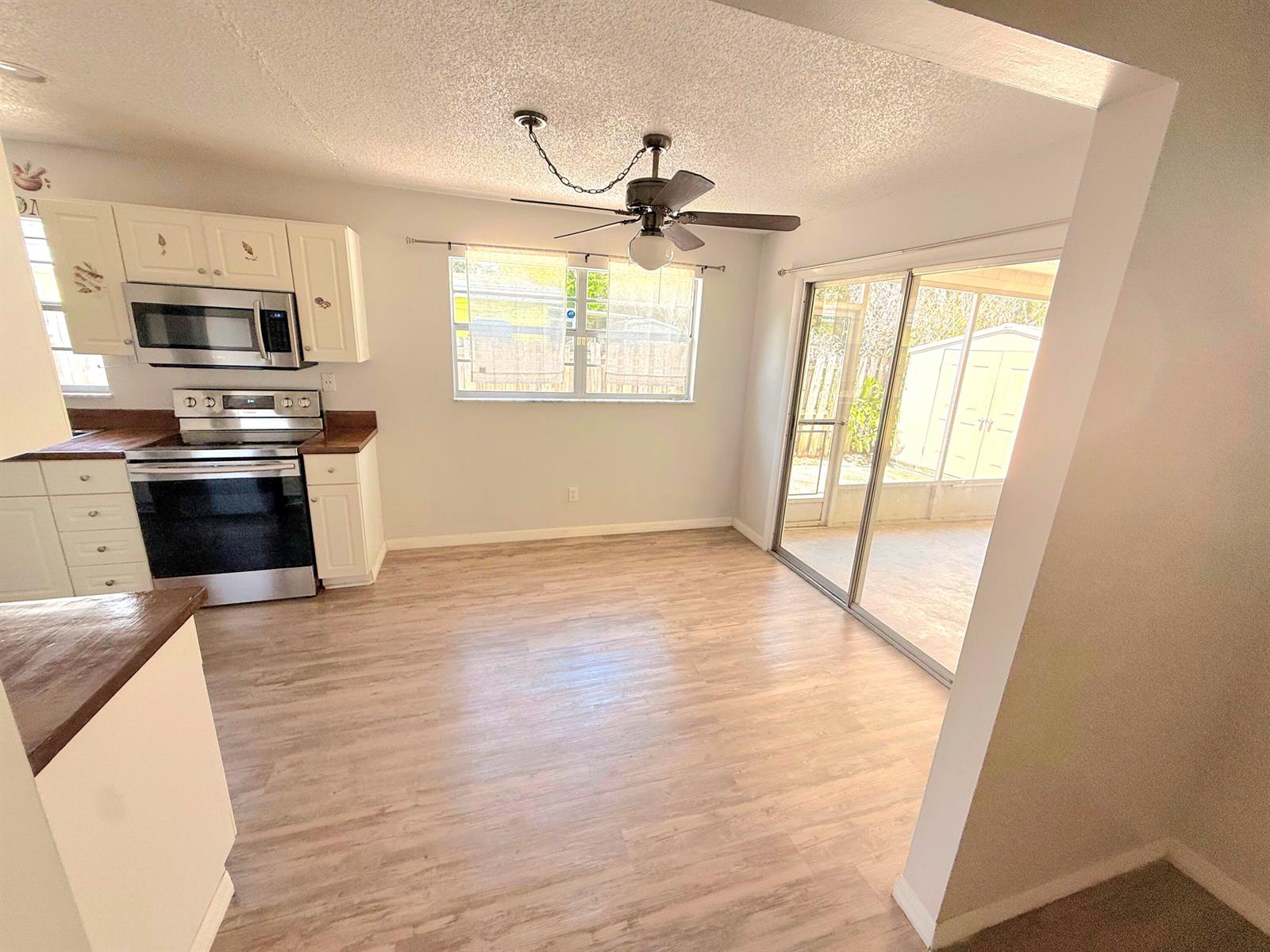 A kitchen and dining area with white cabinets, stainless steel appliances, and sliding glass doors — 2466 44th Avenue, Vero Beach FL 32966, VERO BEACH, FL