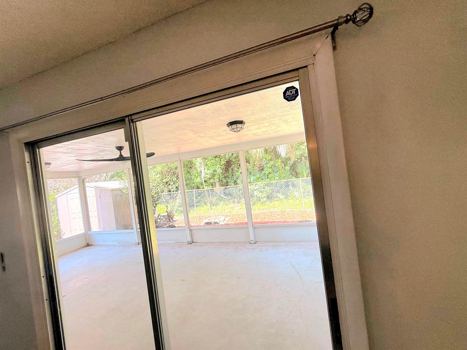 A sliding glass door opens to a covered, screened-in patio with a concrete floor — 2466 44th Avenue, Vero Beach FL 32966, VERO BEACH, FL