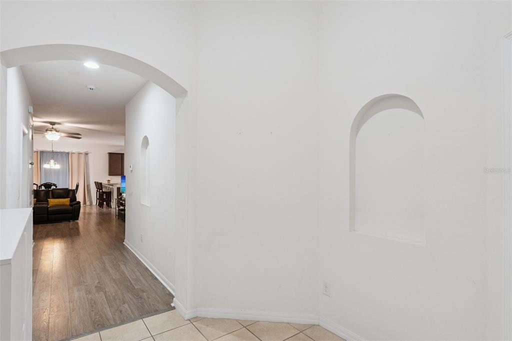 A hallway with an arched entryway leads to a living area with wood-look flooring — 4882 ASHURST STREET, KISSIMMEE, FL