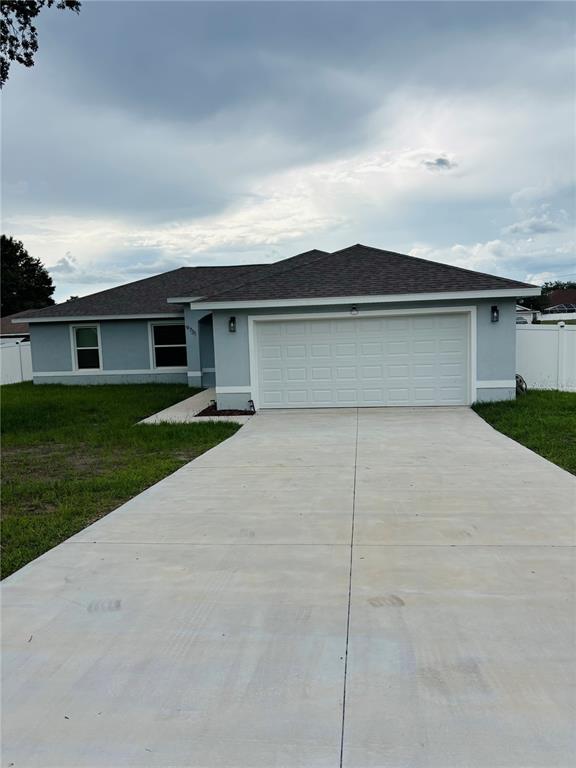 A single-story house with a light blue exterior, a two-car garage, and a concrete driveway — 9731 BAHIA ROAD, OCALA, FL