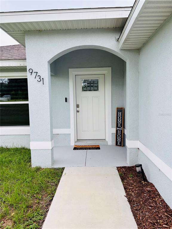 The exterior front entrance features a white door, a concrete walkway, and a house number — 9731 BAHIA ROAD, OCALA, FL