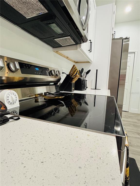 A kitchen features a stainless steel electric range, white countertops, and a microwave above — 9731 BAHIA ROAD, OCALA, FL