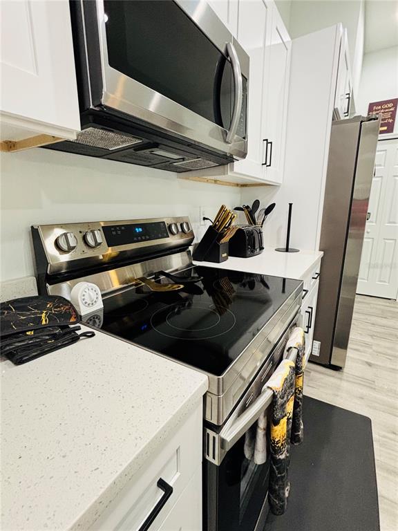 A kitchen features white cabinets, stainless steel appliances, and light-colored quartz countertops — 9731 BAHIA ROAD, OCALA, FL