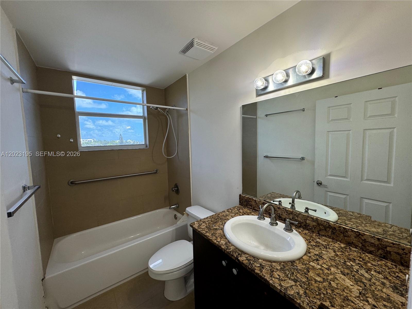 A bathroom features a granite vanity, a toilet, and a bathtub with a shower head — 529 NE 62nd St # 404, Miami FL 33138, MIAMI, FL