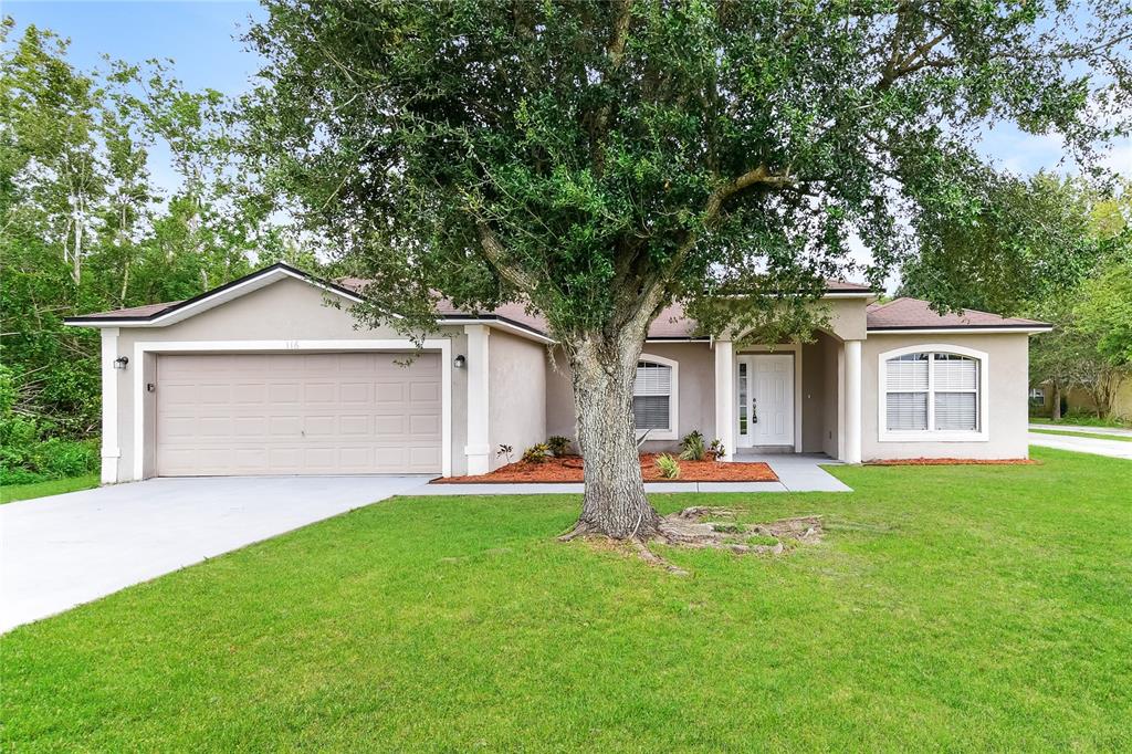 A single-story house with a beige exterior, a two-car garage, and a large front tree — 116 SAN BENITO WAY, KISSIMMEE, FL