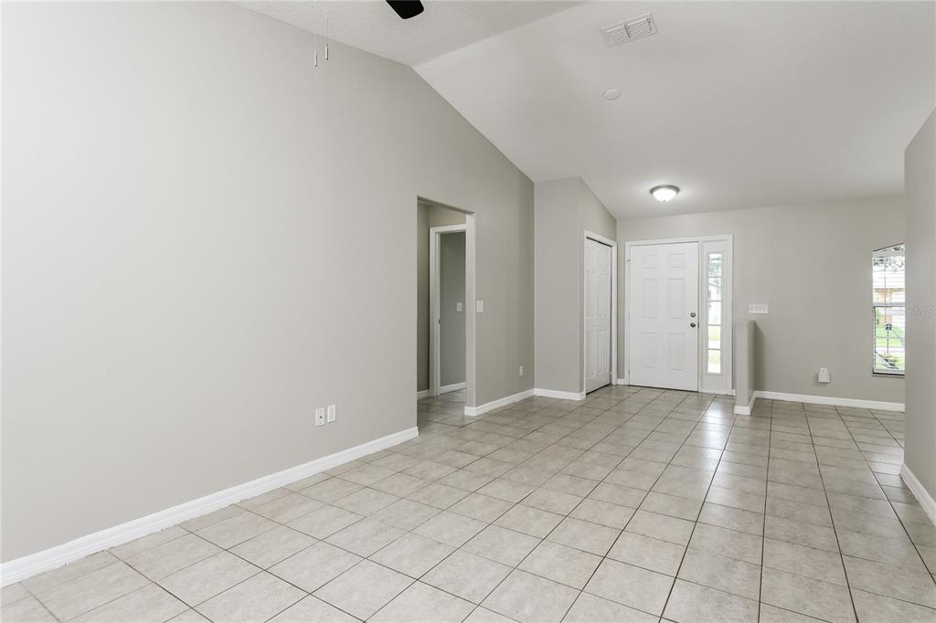 A bright, empty room with light gray walls, vaulted ceilings, and light-colored tile flooring — 116 SAN BENITO WAY, KISSIMMEE, FL