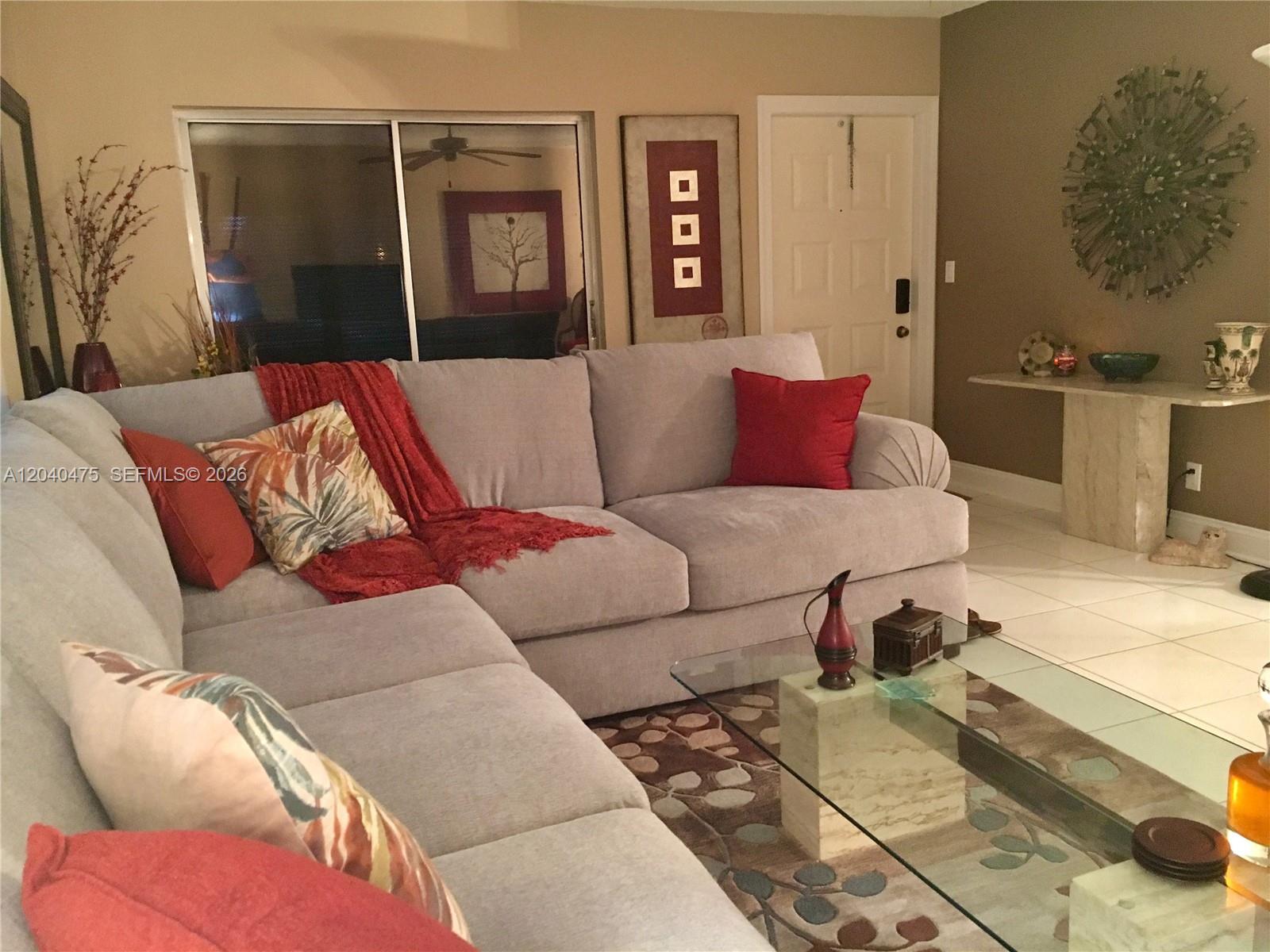 A living room features a light gray sectional sofa, a glass coffee table, and tiled floors — 5025 Lakefront Blvd # D, Delray Beach FL 33484, DELRAY BEACH, FL