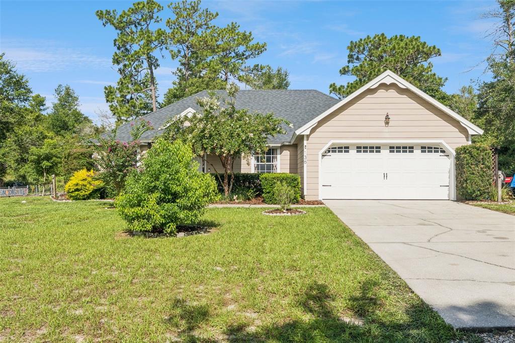 A single-story house with tan siding, a two-car garage, and a front lawn — 136 CHESTNUT AVENUE, ORANGE CITY, FL