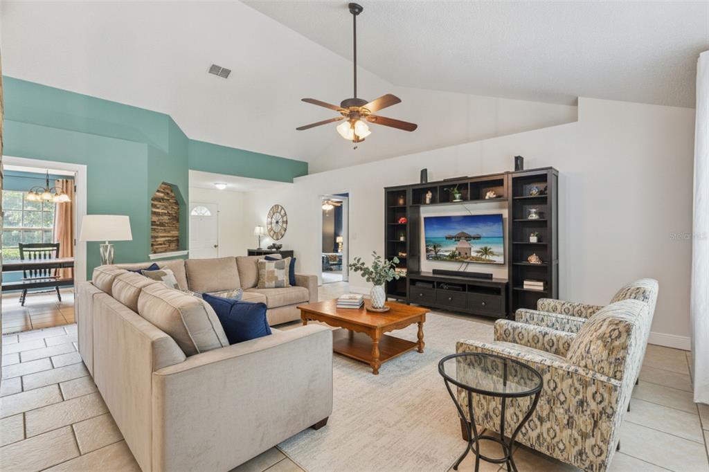 A living room features a vaulted ceiling, a large sectional sofa, and a media console — 136 CHESTNUT AVENUE, ORANGE CITY, FL
