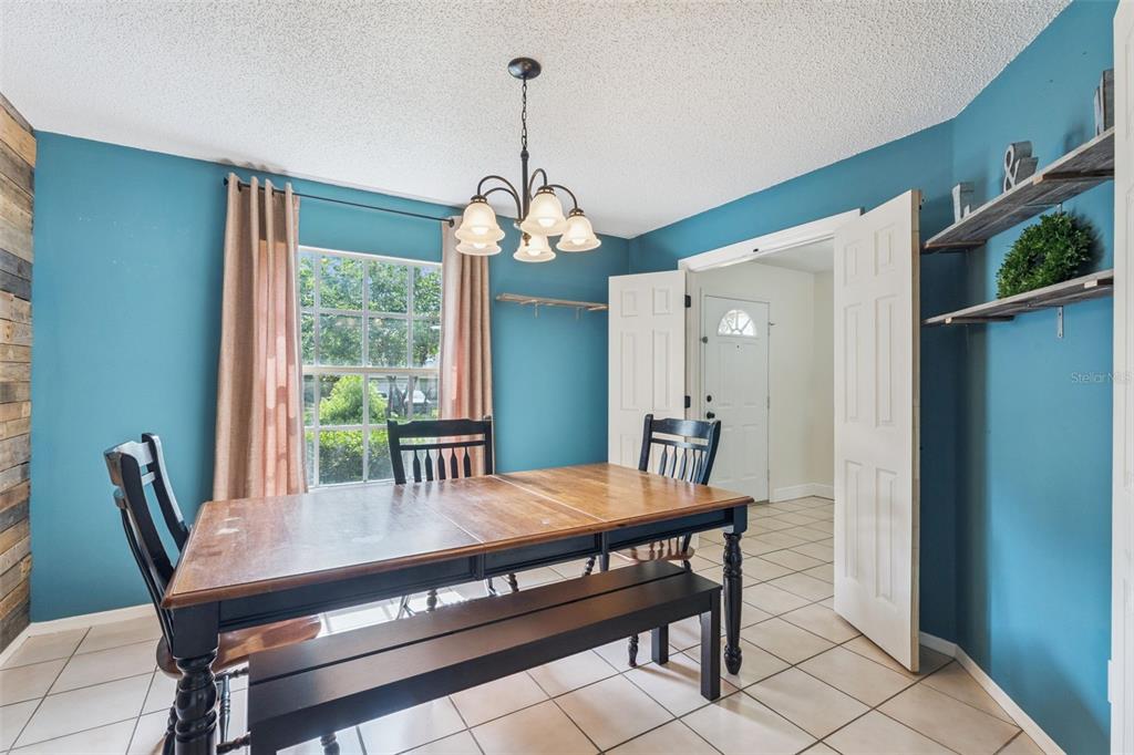 A dining room with blue walls, a wooden table, a bench, and a chandelier — 136 CHESTNUT AVENUE, ORANGE CITY, FL
