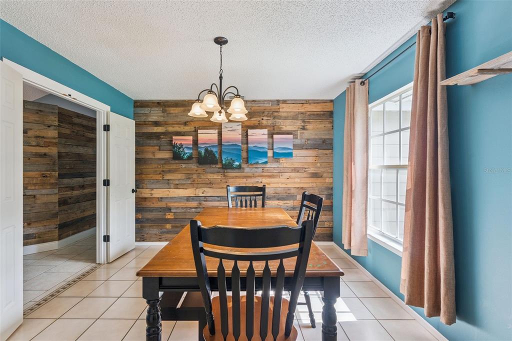 A dining room features a wood-paneled accent wall, a wooden table, and blue painted walls — 136 CHESTNUT AVENUE, ORANGE CITY, FL