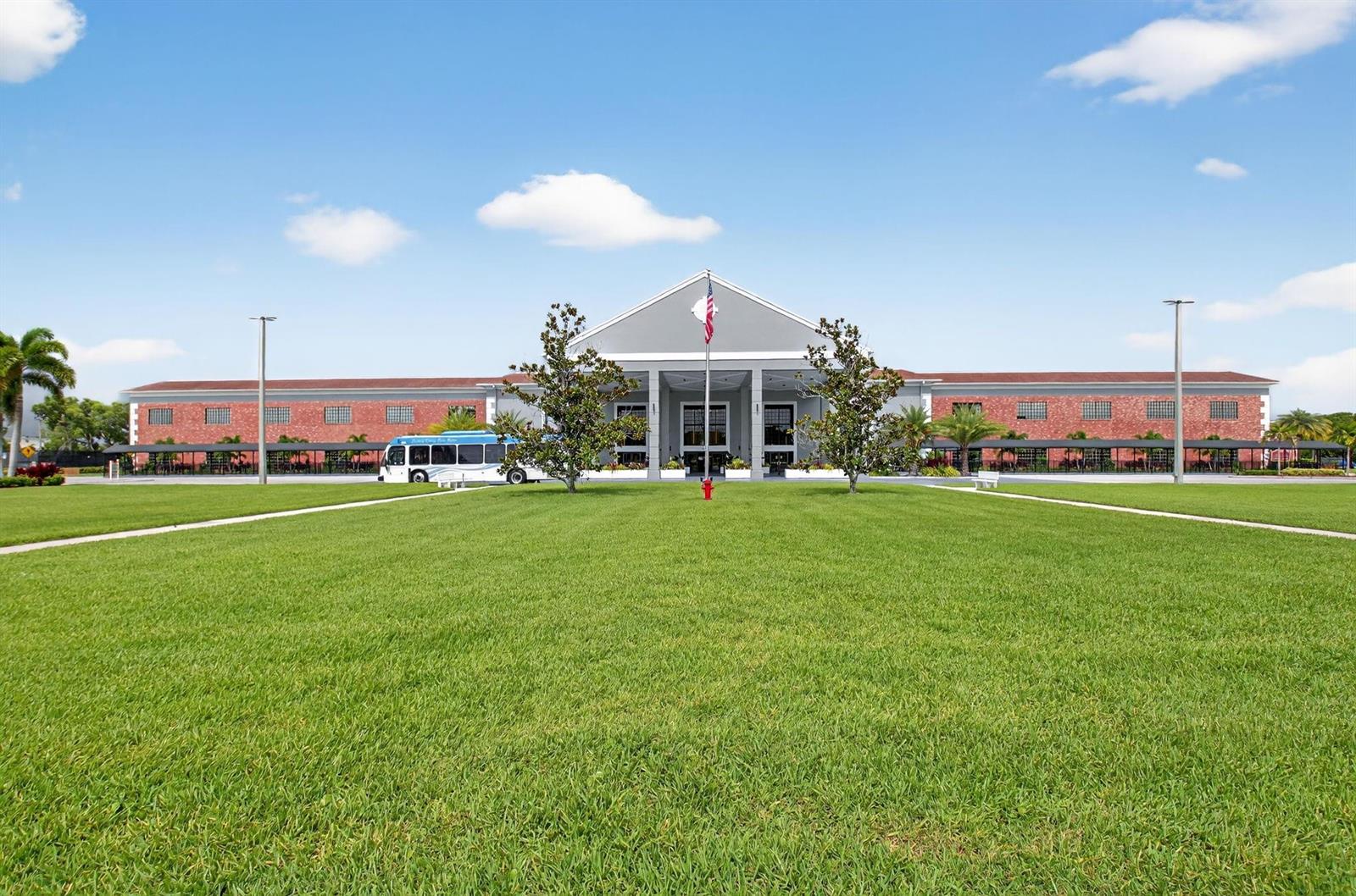 A large, single-story building with a brick facade and a central covered entrance sits behind grass — 3025 Guildford B # 3025, Boca Raton FL 33434, BOCA RATON, FL