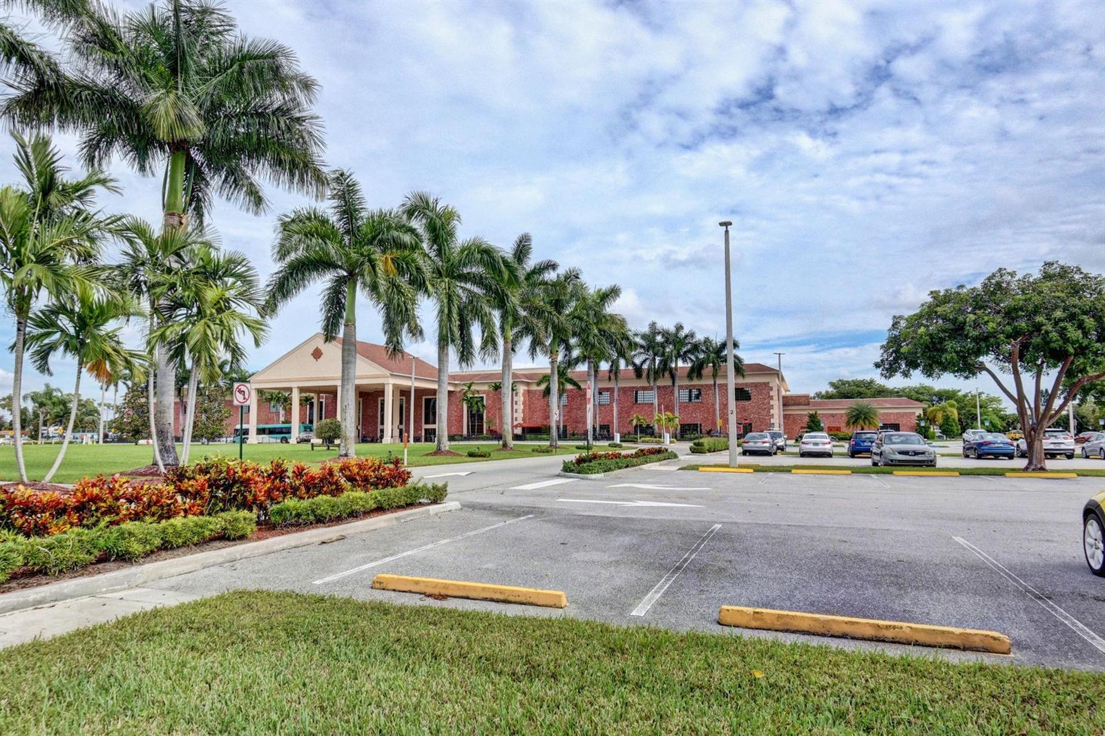 A multi-story brick building with a covered entrance sits behind a parking lot and palms — 3025 Guildford B # 3025, Boca Raton FL 33434, BOCA RATON, FL