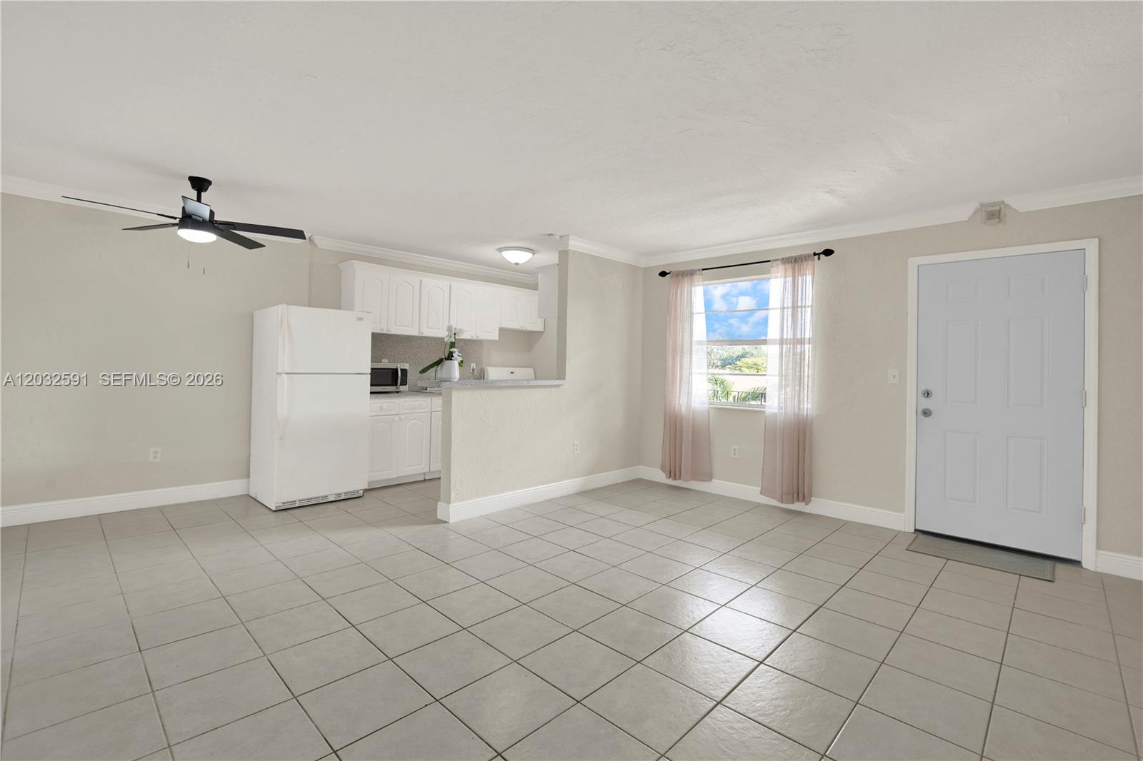 A kitchen with white cabinets and a refrigerator opens into a tiled living area — 3855 SW 79th Ave # 45, Miami FL 33155, MIAMI, FL