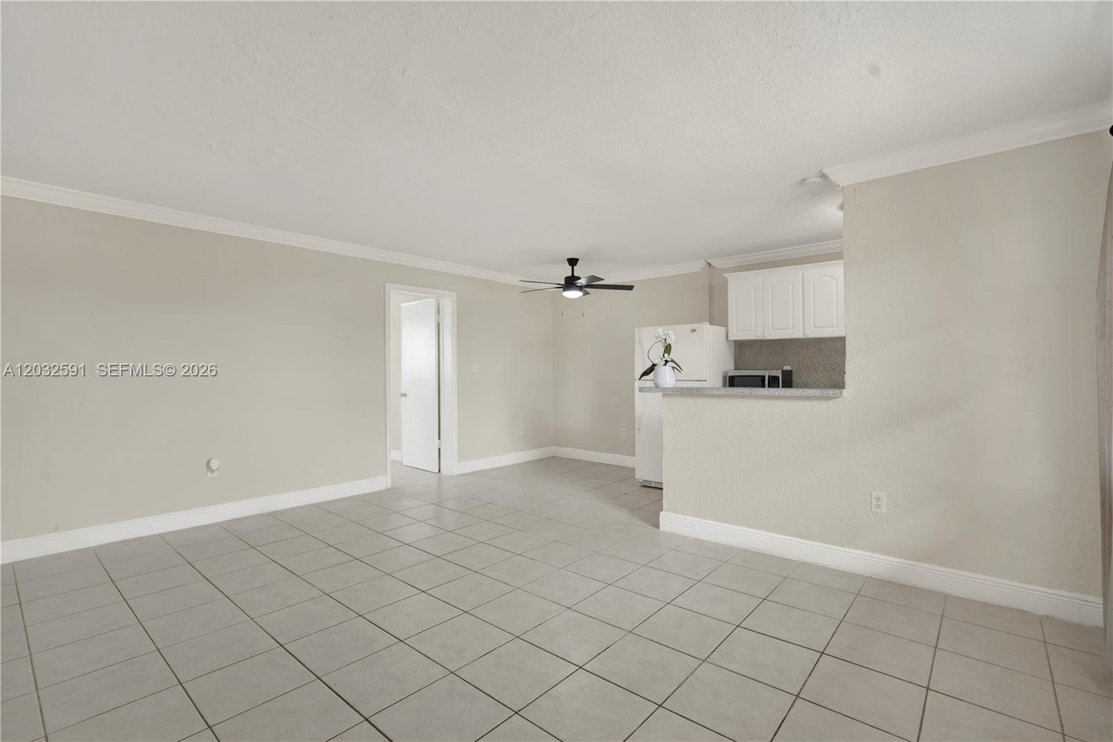 This room features light-colored tile flooring, beige walls, a ceiling fan, and an open kitchen — 3855 SW 79th Ave # 45, Miami FL 33155, MIAMI, FL