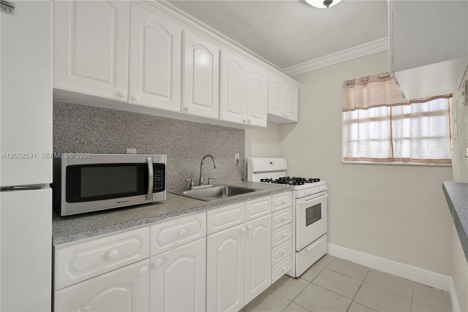 A small kitchen features white cabinets, a granite countertop, a stainless sink, and white appliances — 3855 SW 79th Ave # 45, Miami FL 33155, MIAMI, FL