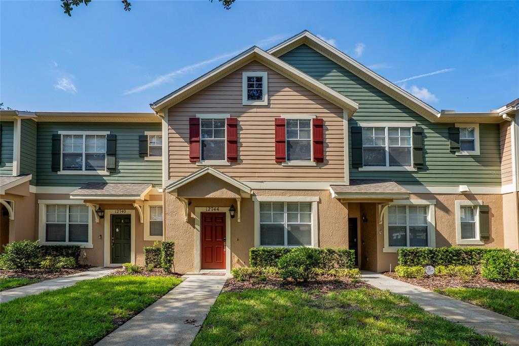 A multi-unit townhouse exterior features tan stucco, green horizontal siding, and a red front door — 12744 LANGSTAFF DRIVE, WINDERMERE, FL