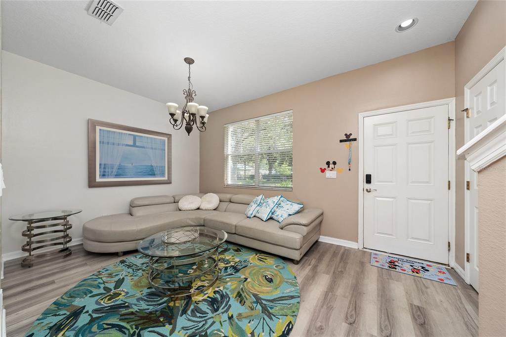 A living room features a beige sectional sofa, a round glass coffee table, and a rug — 12744 LANGSTAFF DRIVE, WINDERMERE, FL