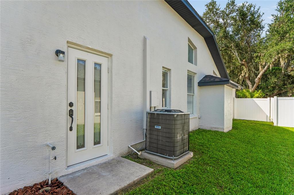 The exterior of a white stucco house features a glass-paneled door and an air conditioning unit — 10150 HERMOSILLO, NEW PORT RICHEY, FL