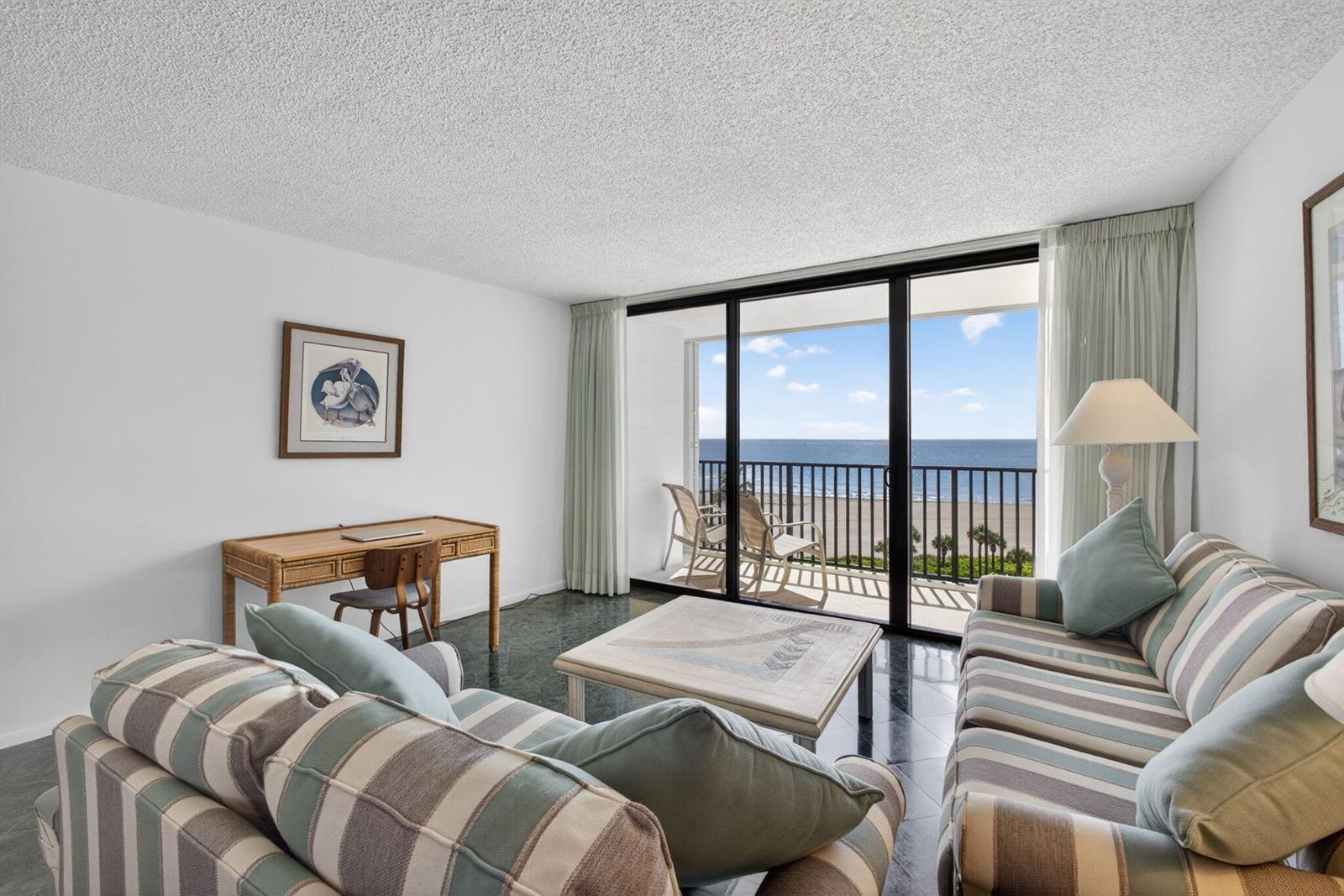 A living room with striped sofas, a desk, and a balcony overlooking the ocean — 400 Ocean Trail Way # 807, Jupiter FL 33477, JUPITER, FL