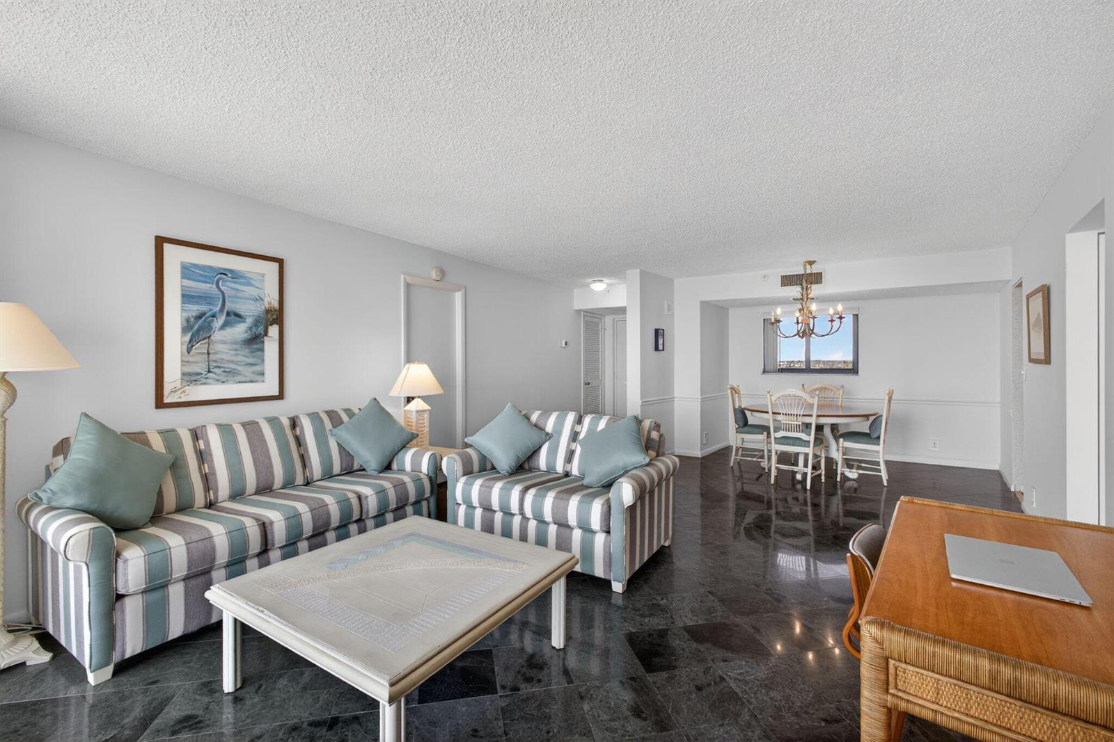A living and dining area features striped furniture, dark tiled floors, and a chandelier — 400 Ocean Trail Way # 807, Jupiter FL 33477, JUPITER, FL
