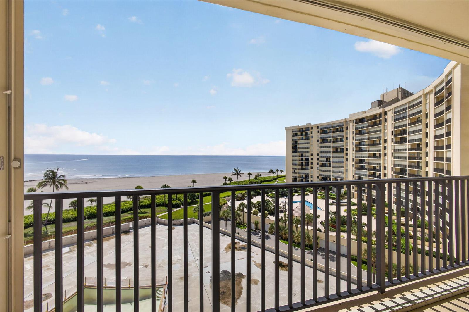 A balcony view overlooking a beach, ocean, and a large multi-story apartment building — 400 Ocean Trail Way # 807, Jupiter FL 33477, JUPITER, FL