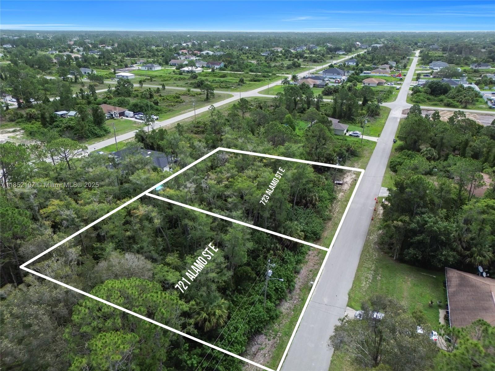 An aerial view shows two adjacent, undeveloped wooded lots bordering a paved residential street — 723 Alamo ST E, Lehigh Acres FL 33974, LEHIGH ACRES, FL
