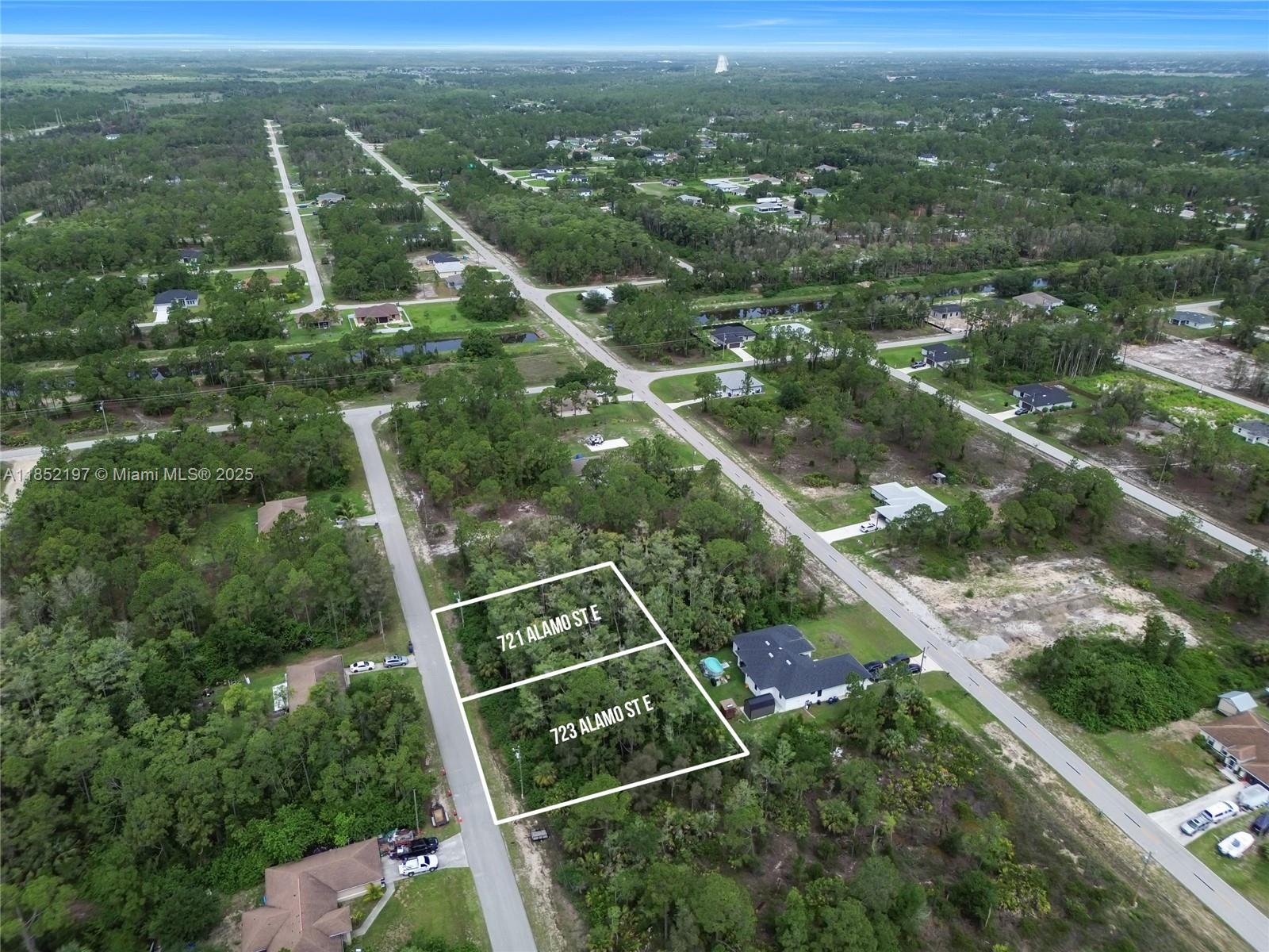 An aerial view shows two adjacent vacant lots outlined in white within a wooded neighborhood — 723 Alamo ST E, Lehigh Acres FL 33974, LEHIGH ACRES, FL