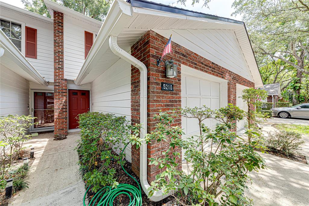 A brick and white siding house exterior features a red front door and garage — 5210 LAZY OAKS DRIVE UNIT 5210, WINTER PARK, FL