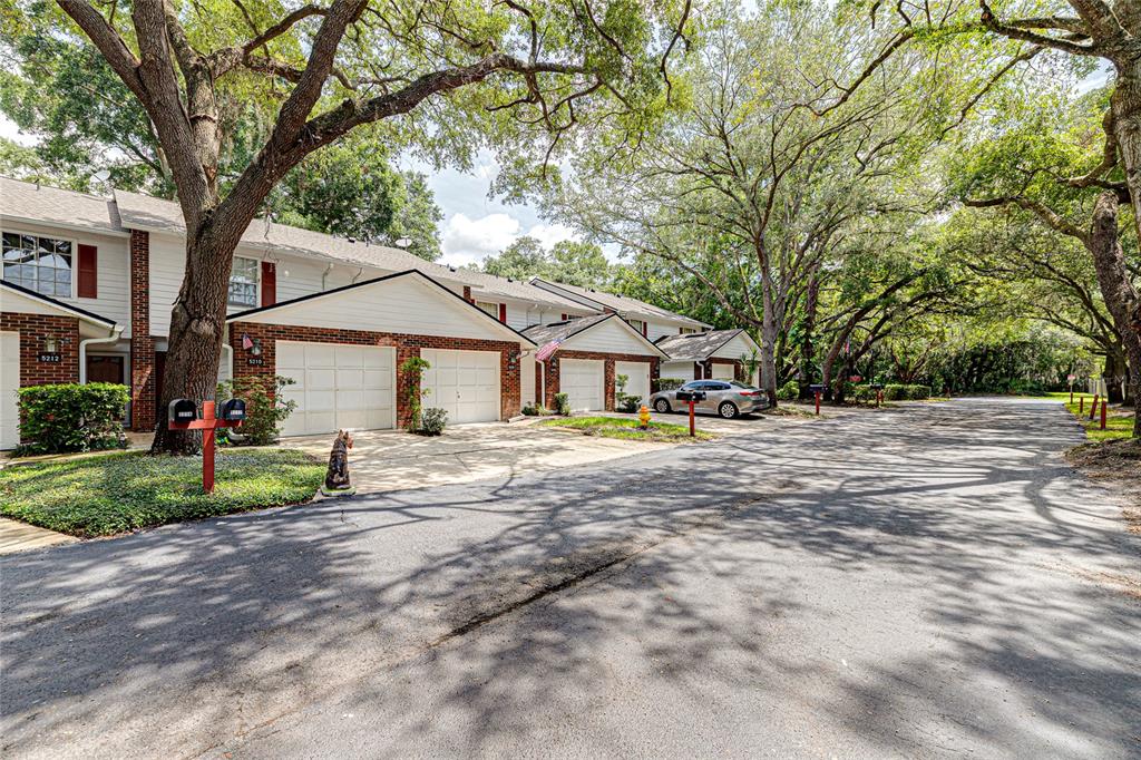 A row of attached townhomes with brick and white siding features garages and mature trees — 5210 LAZY OAKS DRIVE UNIT 5210, WINTER PARK, FL