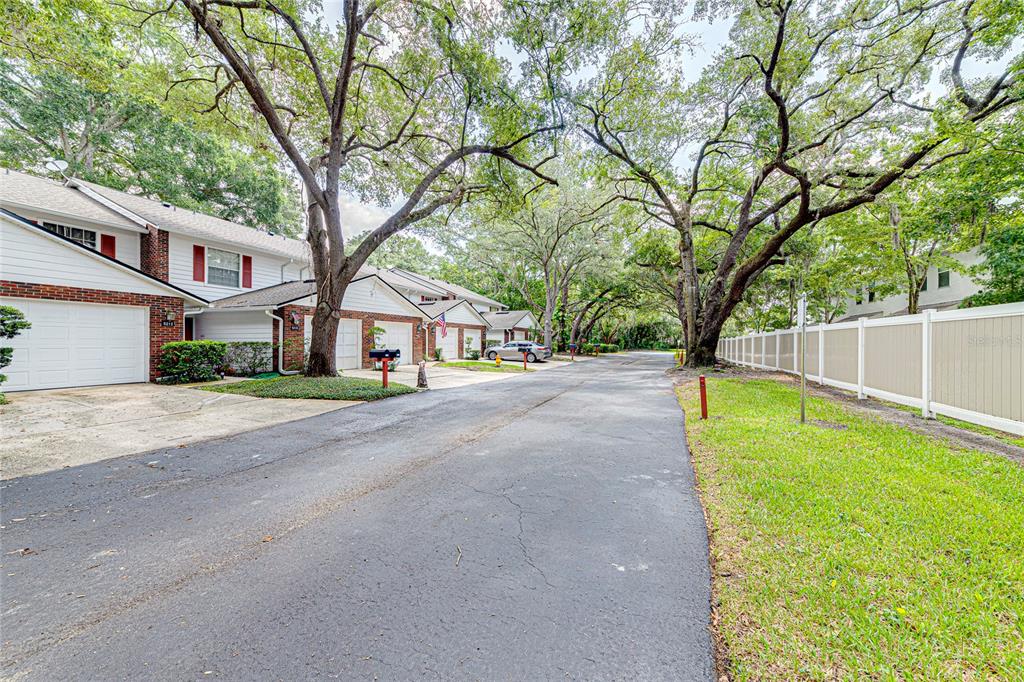 A paved street leads past a row of townhomes with garages and large oak trees — 5210 LAZY OAKS DRIVE UNIT 5210, WINTER PARK, FL