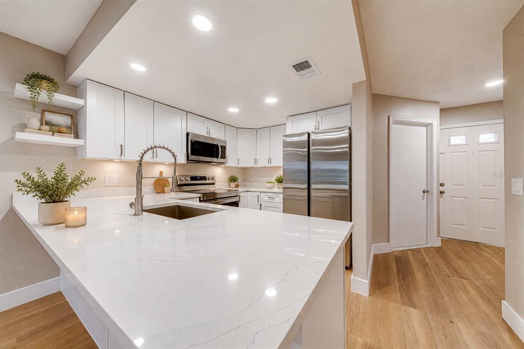 A modern kitchen features white cabinets, stainless steel appliances, and a large quartz-topped island — 5210 LAZY OAKS DRIVE UNIT 5210, WINTER PARK, FL
