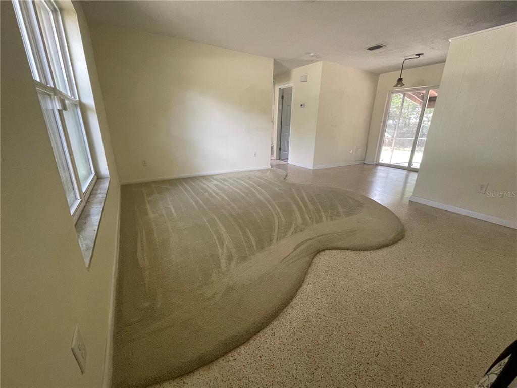 An interior view of a living area featuring a raised carpeted section and tile flooring — 1324 WHITEWOOD DRIVE, DELTONA, FL
