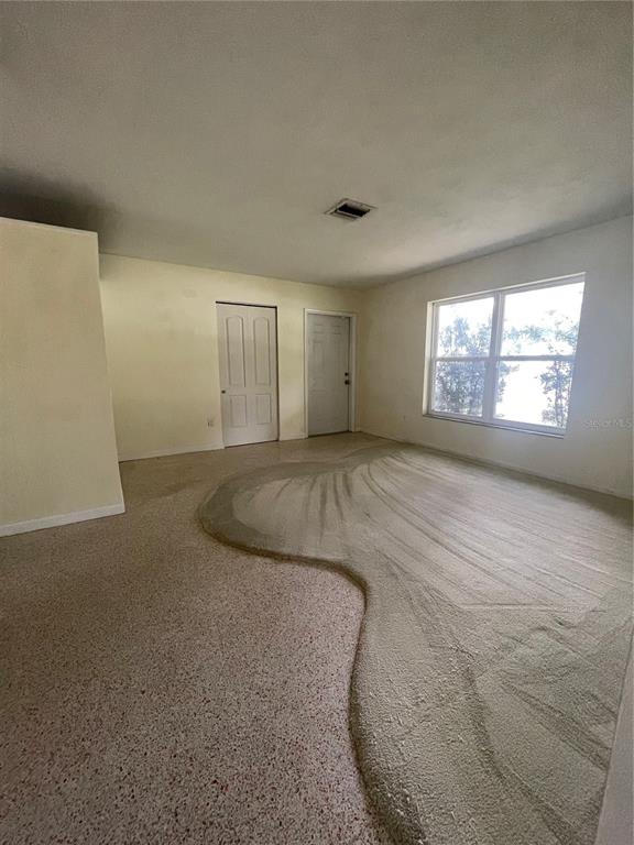 An interior room features a mix of speckled terrazzo flooring and a large carpeted area — 1324 WHITEWOOD DRIVE, DELTONA, FL
