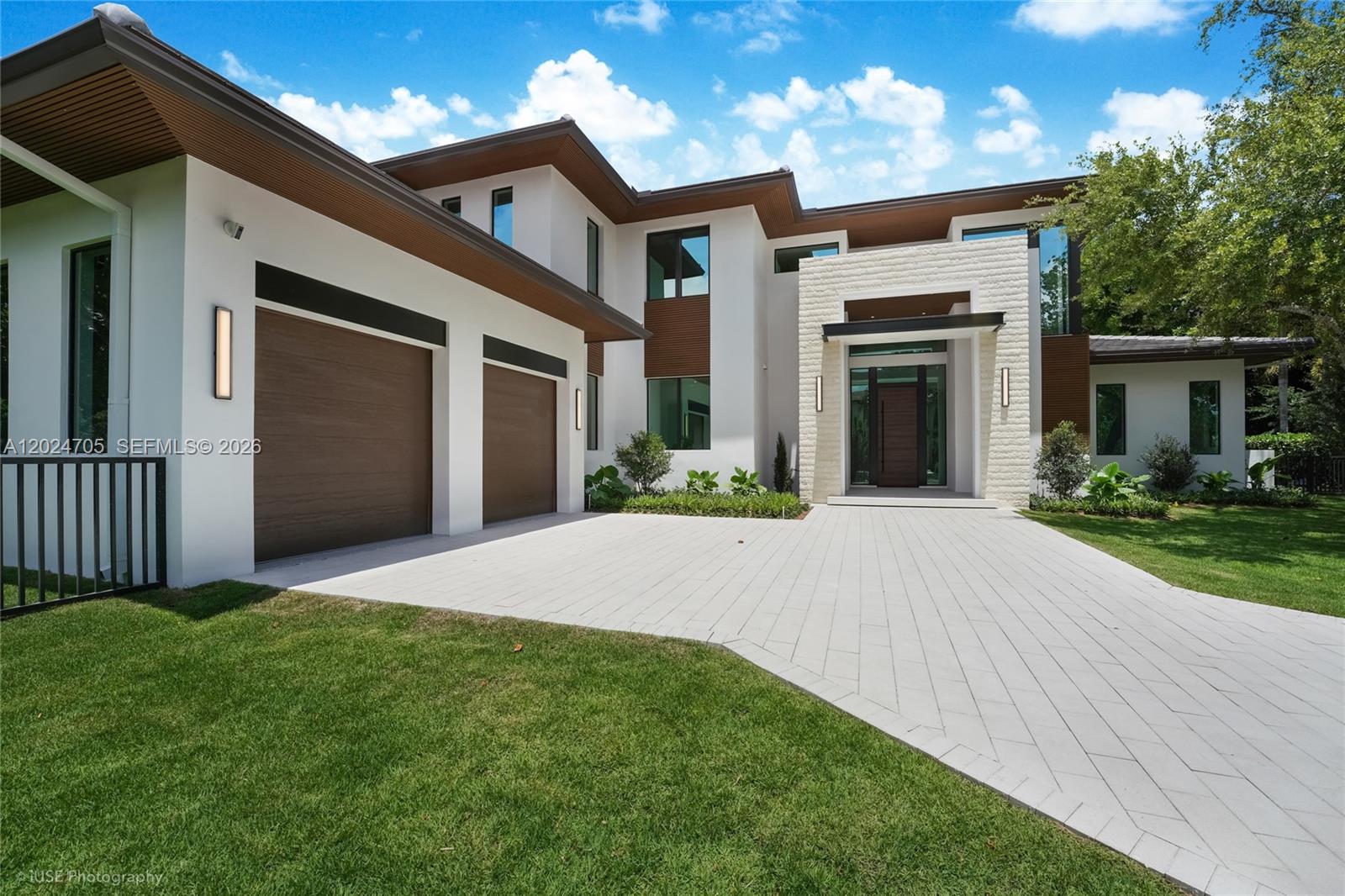 A modern two-story house features a white exterior, wood accents, and a paved driveway — 9405 SW 72nd Ct, Pinecrest FL 33156, PINECREST, FL