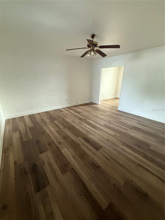 An empty room features wood-look flooring, white walls, and a ceiling fan — 6715 N ARMENIA AVENUE, TAMPA, FL