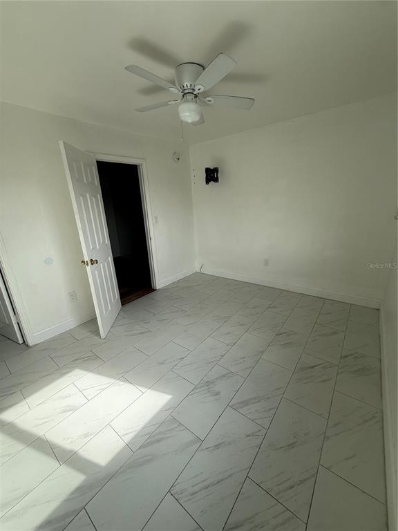 A bedroom with white walls, a ceiling fan, and white marble-look tile flooring — 6715 N ARMENIA AVENUE, TAMPA, FL