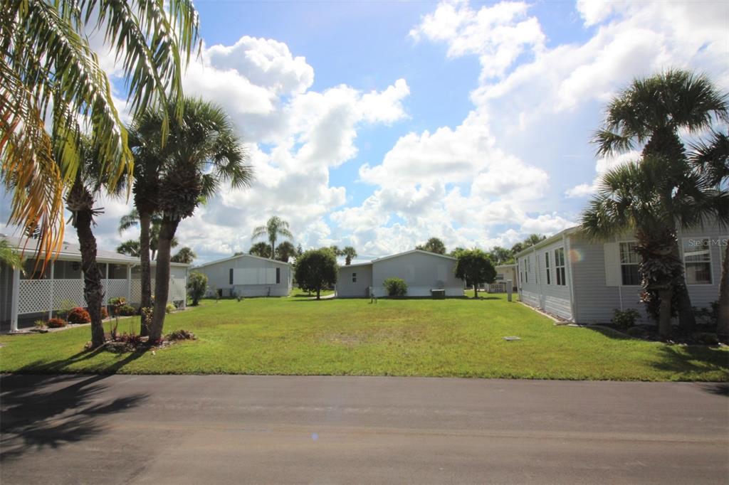 A grassy lot sits between two manufactured homes under a bright, cloudy sky — 2100 KINGS HIGHWAY UNIT 145, PORT CHARLOTTE, FL