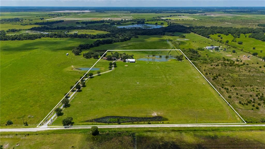 An aerial view shows a rural property with a house, ponds, and fenced pasture land — 12241 SW GORDON HAY ROAD, ARCADIA, FL