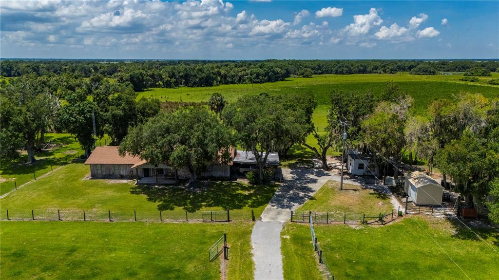 An aerial view shows a single-story house with a metal roof, driveway, and outbuildings — 12241 SW GORDON HAY ROAD, ARCADIA, FL