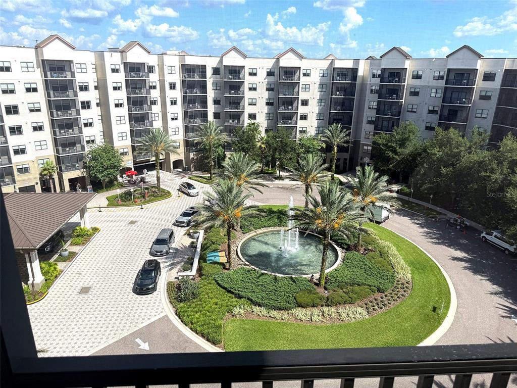 An elevated view of a multi-story apartment complex courtyard featuring a central fountain and landscaping — 14501 GROVE RESORT AVENUE UNIT 2703, WINTER GARDEN, FL