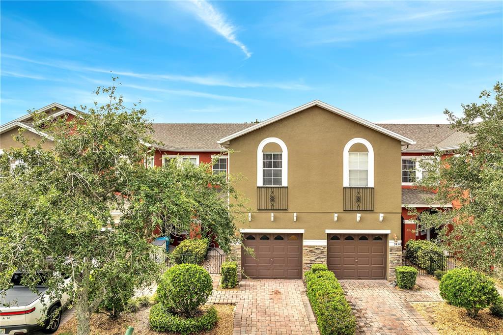 An exterior view of a two-story townhouse with two garage doors and arched windows — 9454 SILVER BUTTONWOOD STREET, ORLANDO, FL
