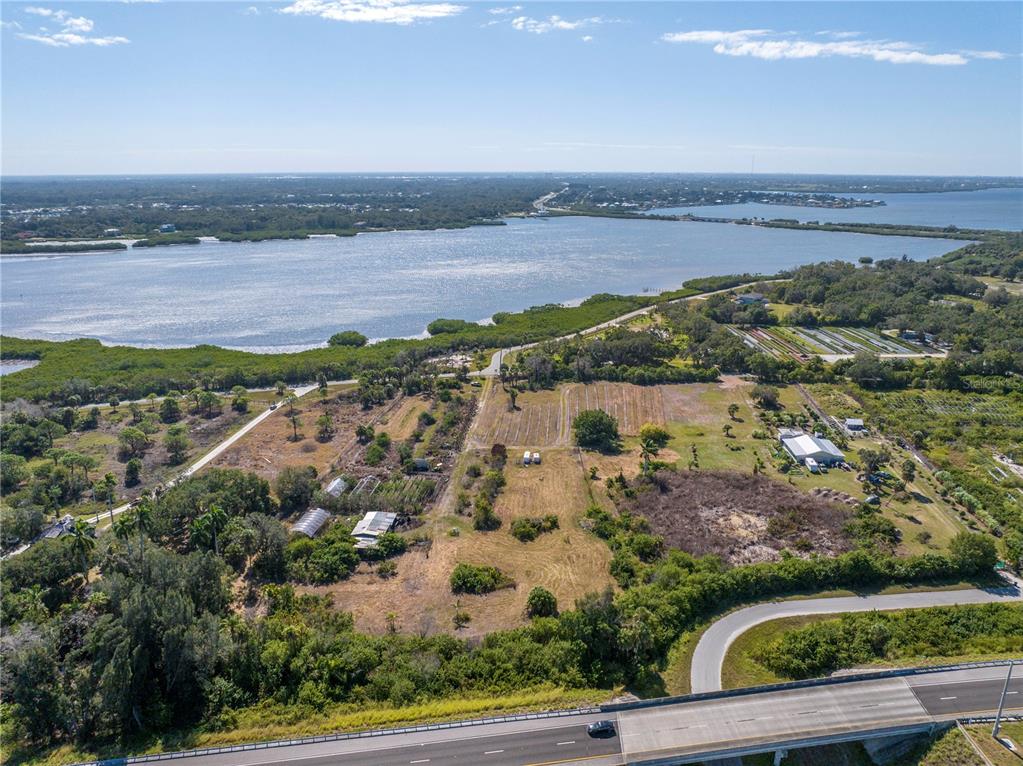 An aerial view shows a rural property with greenhouses and fields near a large body — 282 TERRA CEIA ROAD, PALMETTO, FL