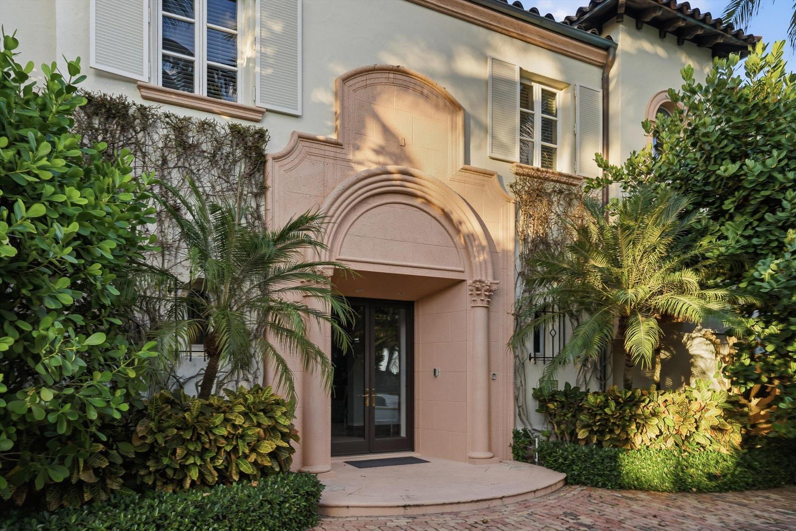 A pink stone arched entryway leads to a dark glass door on a stucco house — 240 N Ocean Boulevard, Palm Beach FL 33480, PALM BEACH, FL