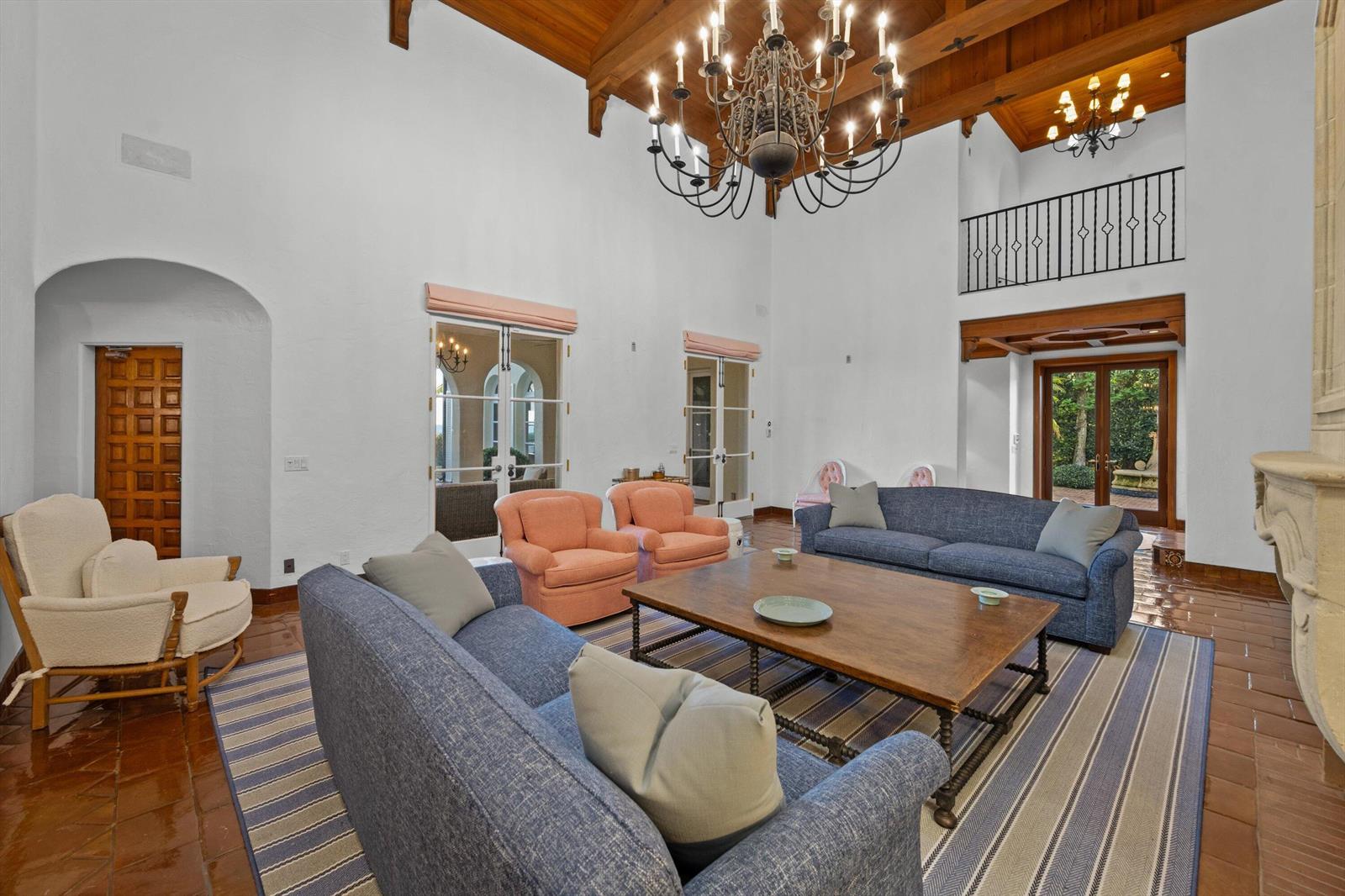 A spacious living room features a vaulted wood ceiling, chandeliers, and blue and peach furniture — 240 N Ocean Boulevard, Palm Beach FL 33480, PALM BEACH, FL